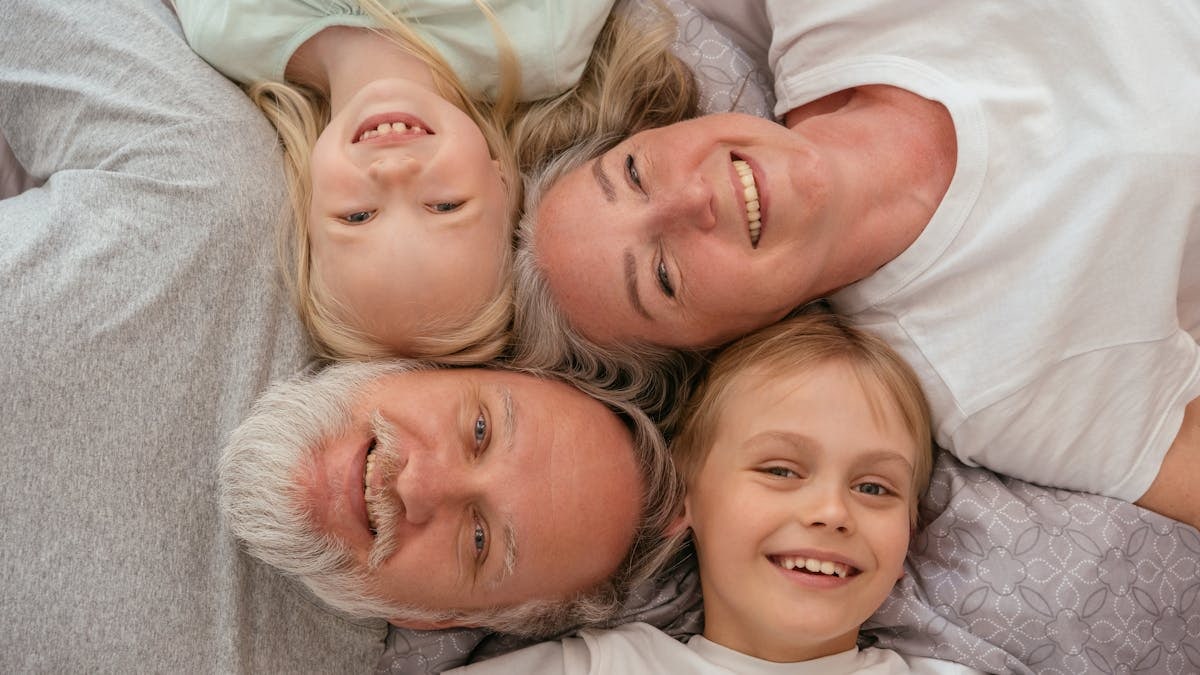 A joyful multigenerational family lying down and smiling together, displaying warmth and affection.